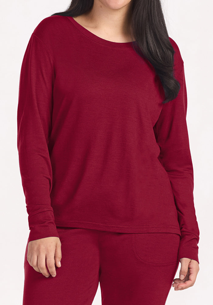 A person wears a wrinkle-resistant, deep red Ashlie Lounge Top - Beet Red crewneck lounge top.