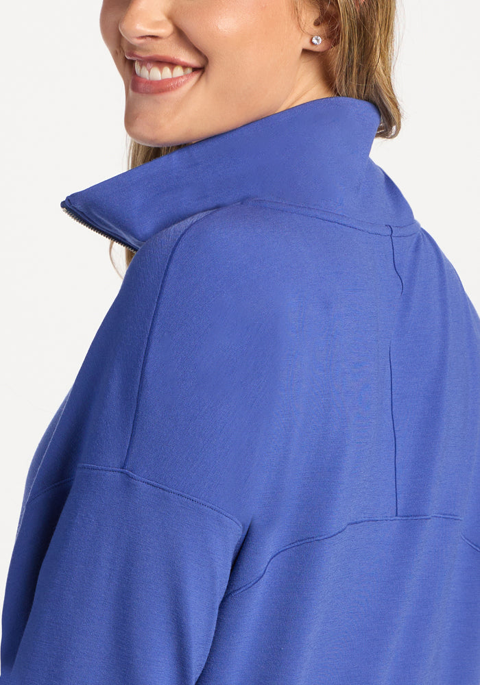 A person wearing a royal blue moisture-wicking merino wool Tori 1/4 Zip pullover.
