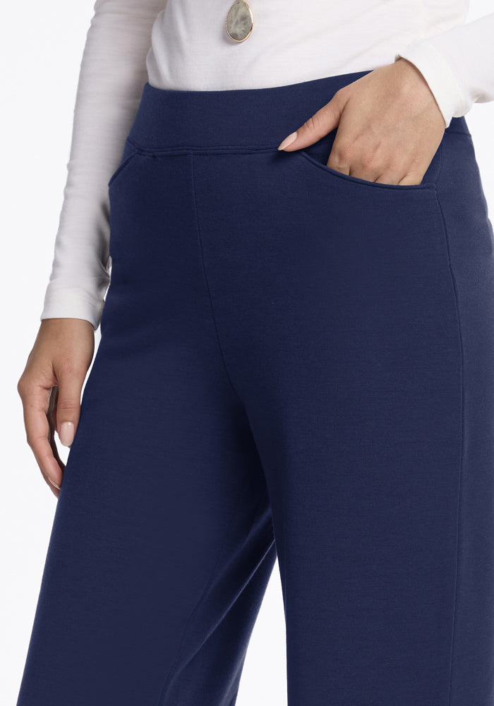 Someone wears Woolx Ellie Wide Leg Pants in Ocean Cavern and a white long sleeve, with one hand in their pocket.