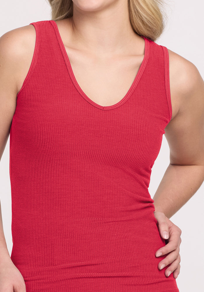 Woman wears Woolx Vivi Ribbed Tank in Berry Ice Pop, sleeveless and cool, hand on hip, plain background.