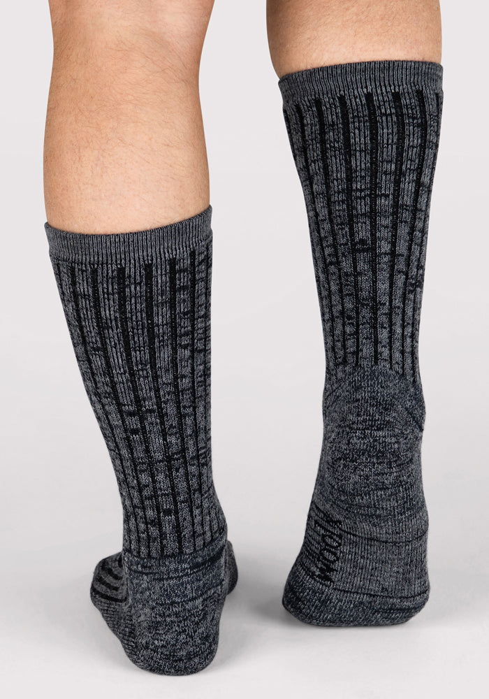 A close-up of two legs wearing Mens Joey Crew Socks - Stone Grey by Woolx, standing on a light background.