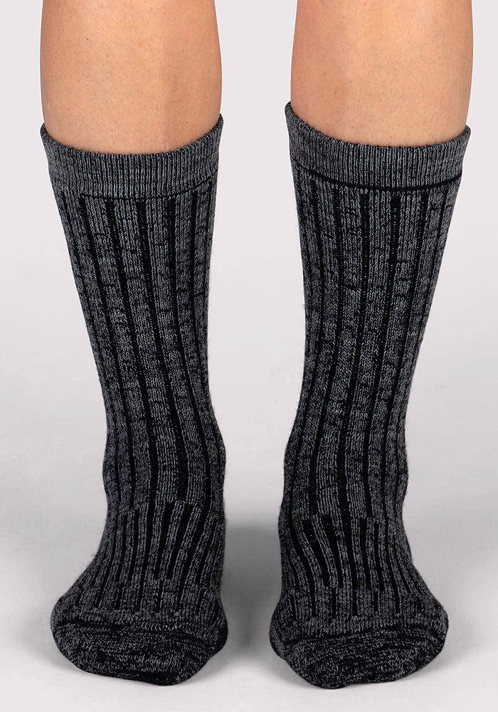 A close-up of two feet wearing Woolx Womens Joey Crew Socks in Stone Grey, standing on a light-colored surface.