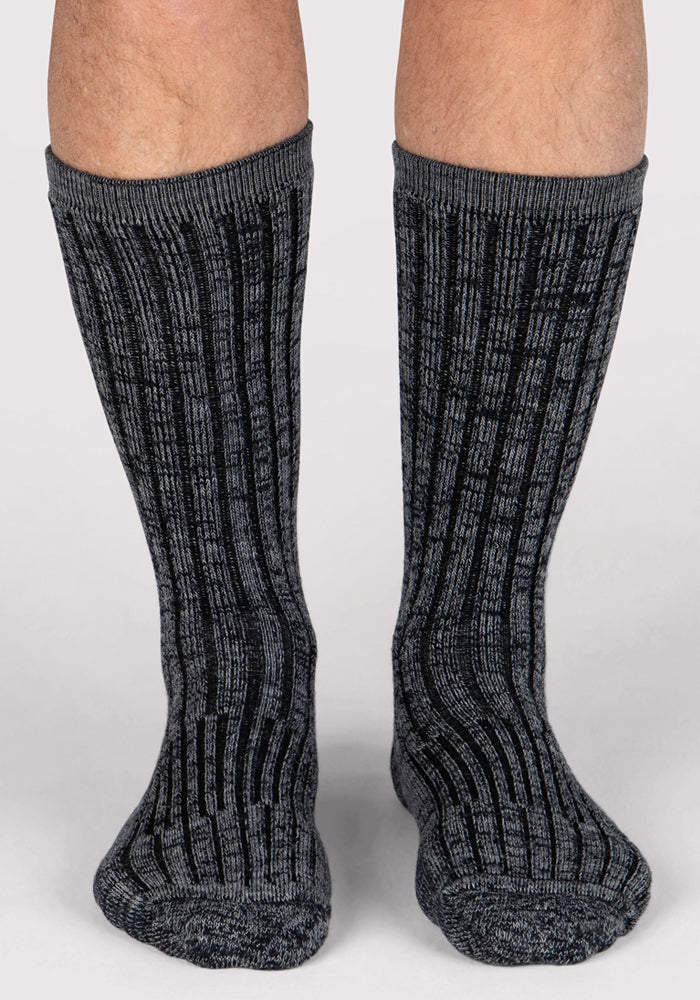 A close-up of a person's lower legs wearing Woolx Mens Joey Crew Socks in Stone Grey, with feet side by side on a light background.