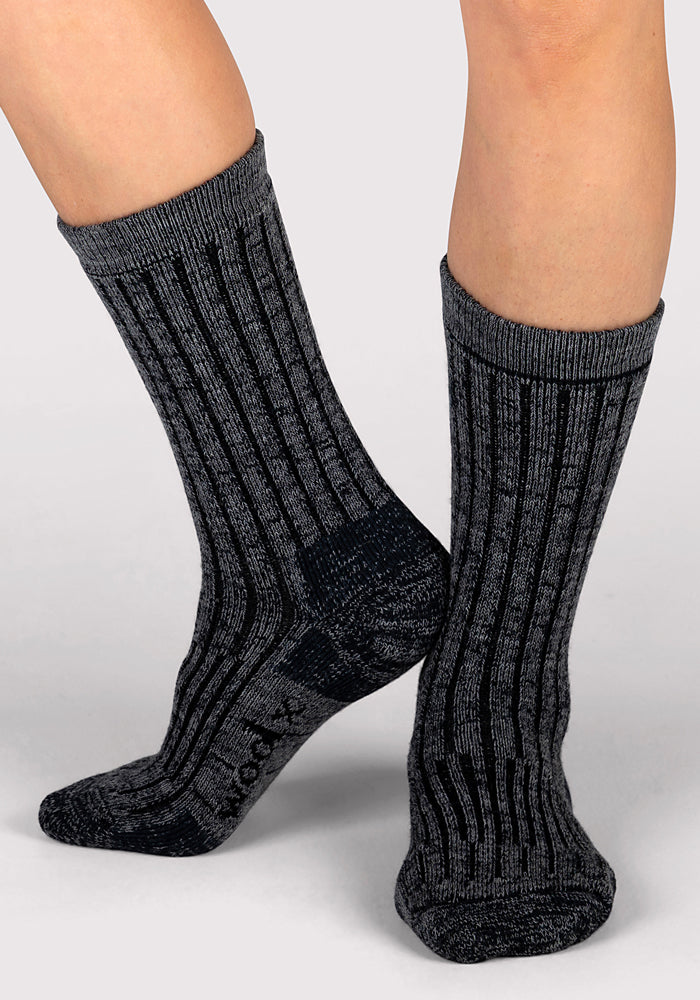 Wearing Woolx Womens Joey Crew Socks in Stone Grey, a person stands on a light gray surface with one foot slightly ahead of the other.