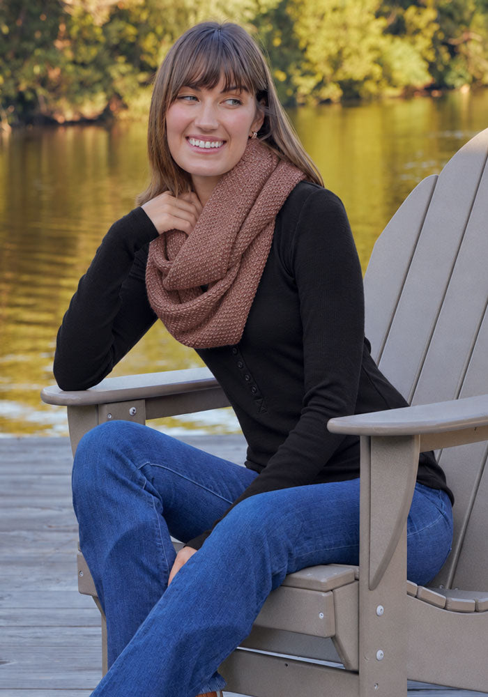Woman by a lake, smiling in a Woolx Noelle Infinity Scarf - Sable Heather, black top, and blue jeans.