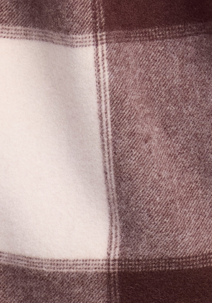 The fabric's rich texture and subtle plaid design echo the classic Sawyer Shacket by Woolx in "Chai Latte Plaid," offering an enticing look at its intricate weave.