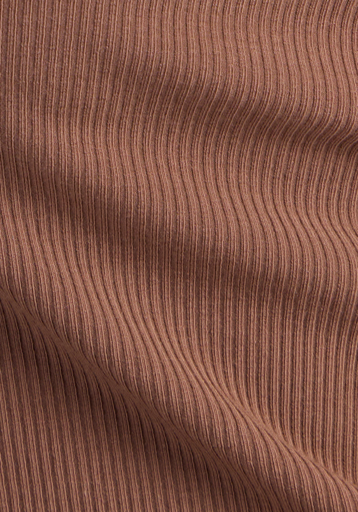Close-up of the Woolx Delia Ribbed Short Sleeve in Sienna Kiss, showing the brown ribbed fabric with vertical lines, soft shadows, and gentle folds that highlight its wrinkle-resistant Merino wool texture.