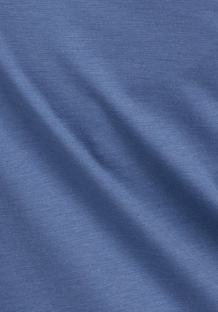 Close-up of the Woolx Hazel Tunic - Skyline, featuring blue, lightweight Merino wool fabric with soft diagonal folds, a smooth textured surface, and temperature-regulating properties for lasting comfort.