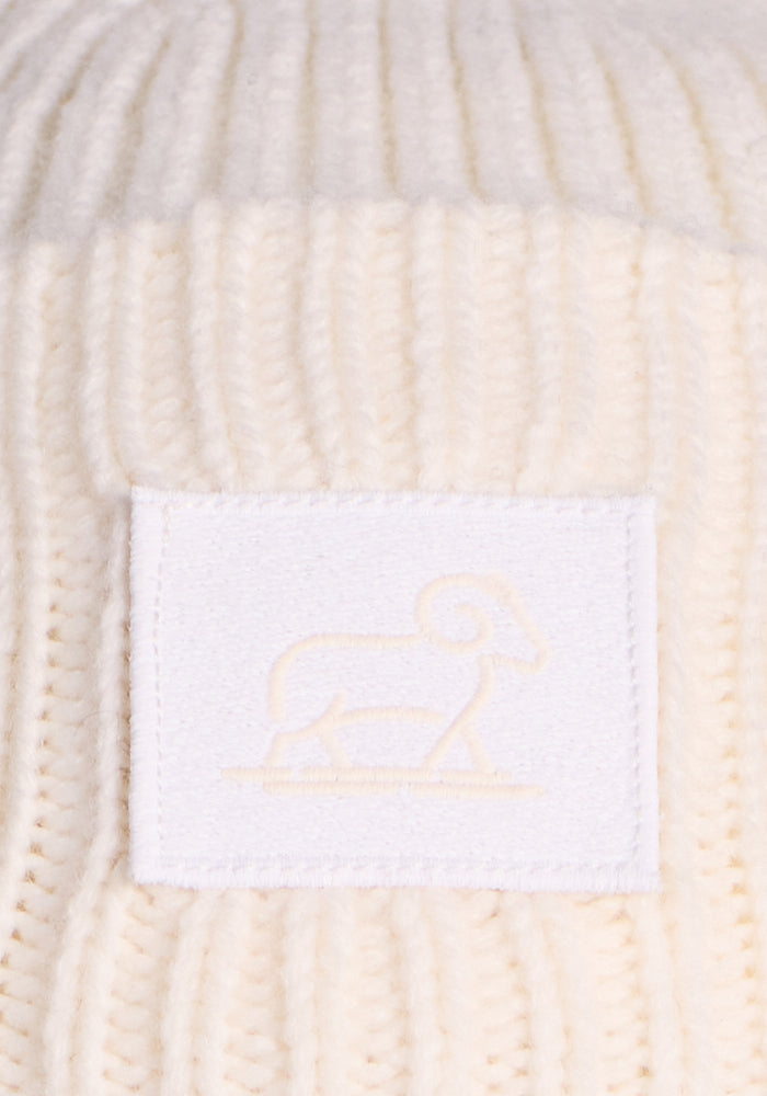 Close-up of the Woolx Ria Chunky Beanie in Buttercream, featuring a white patch with an embroidered ram outline—a cozy winter essential.