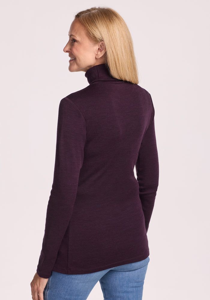 A woman with straight blonde hair is shown from the back, wearing the Woolx Peyton Turtleneck in Deep Plum and light blue jeans against a plain light background.