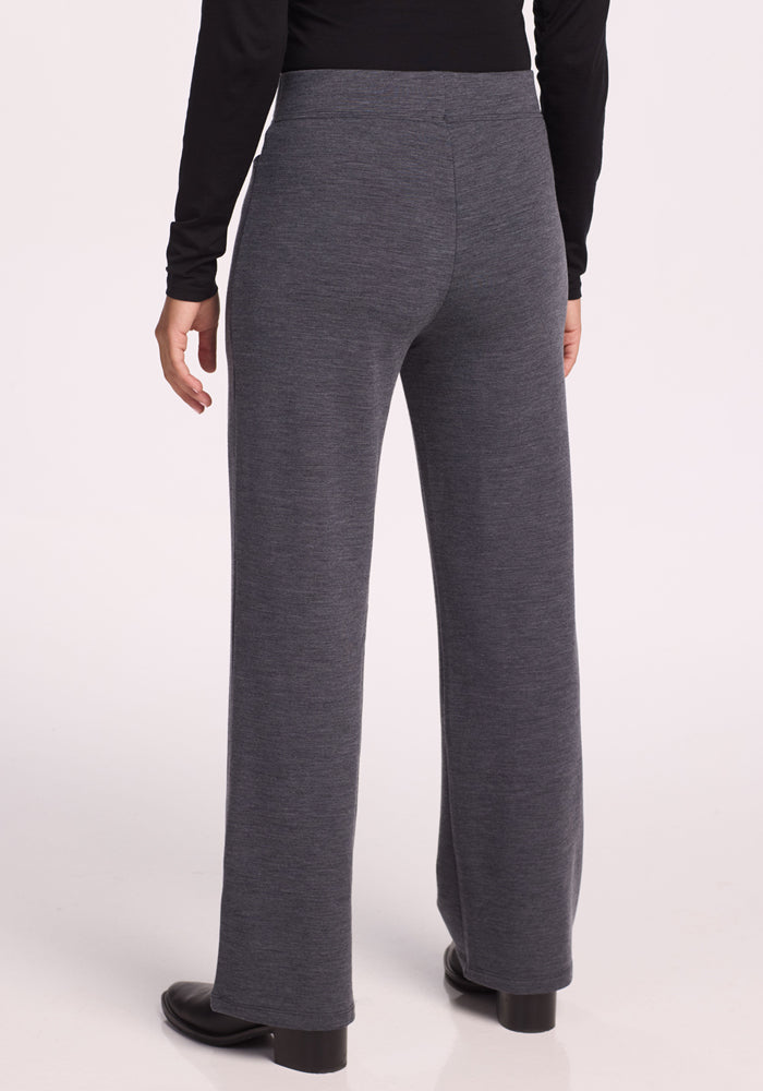 A person wearing Woolx Ellie Wide Leg Pants in Cinder Melange with a black long-sleeve top and black shoes, shown from the back against a plain light background.