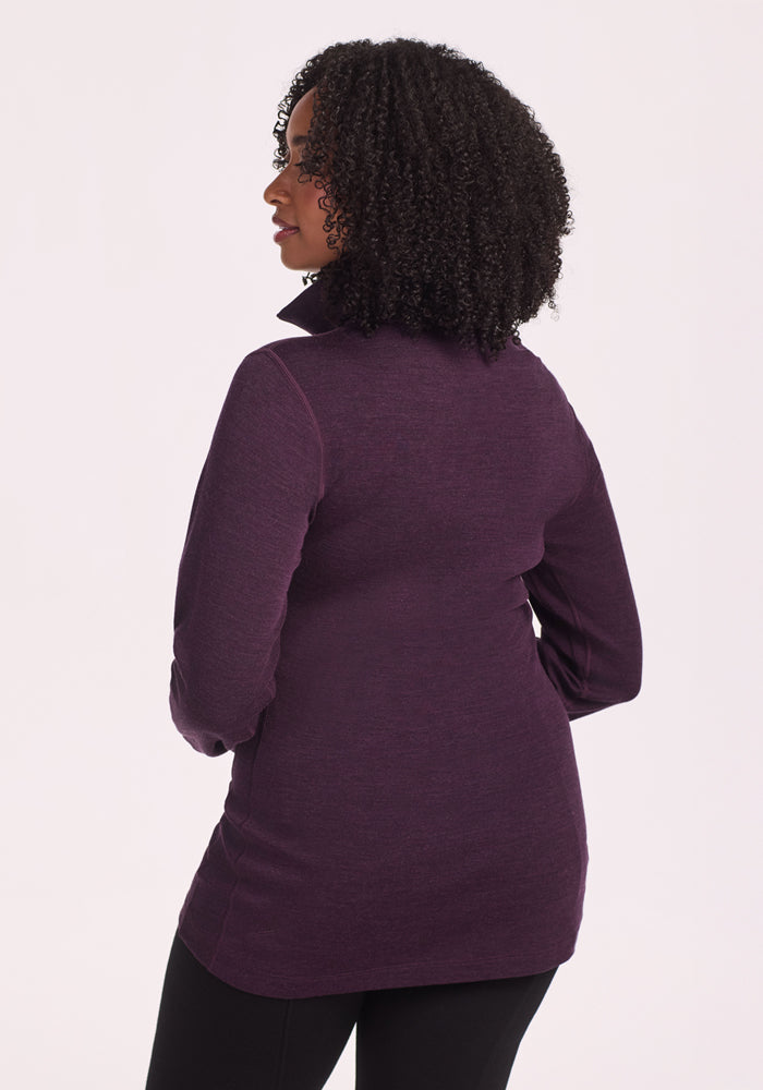 A woman with curly hair, seen from behind against a light background, wears the moisture-wicking Woolx Brooke 1/4 Zip in Deep Plum with black pants.