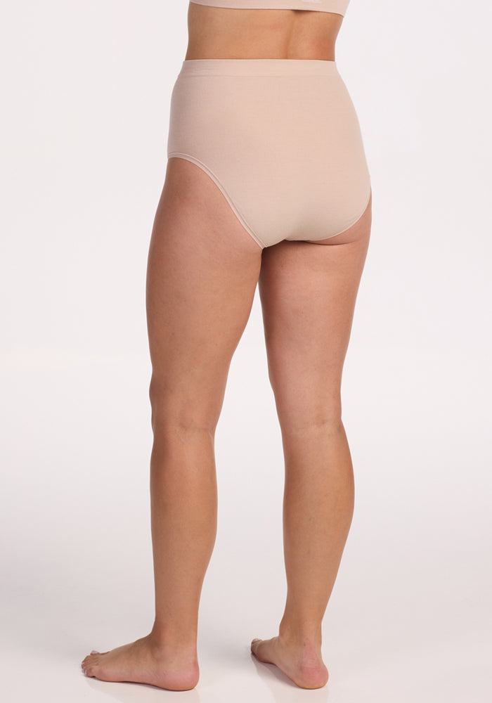 A person stands barefoot on a white background, shown from the back, wearing Woolx's Mabel Full Coverage Underwear in Sand—a high-waisted, seamless set designed for maximum comfort.