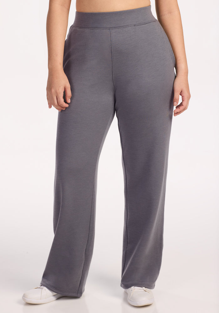 A person models Woolx Bree Lounge Pants in Arctic Dusk, styled as high-waisted, loose-fitting lounge sweatpants with white sneakers. Only the lower torso and legs are visible against a plain white background.