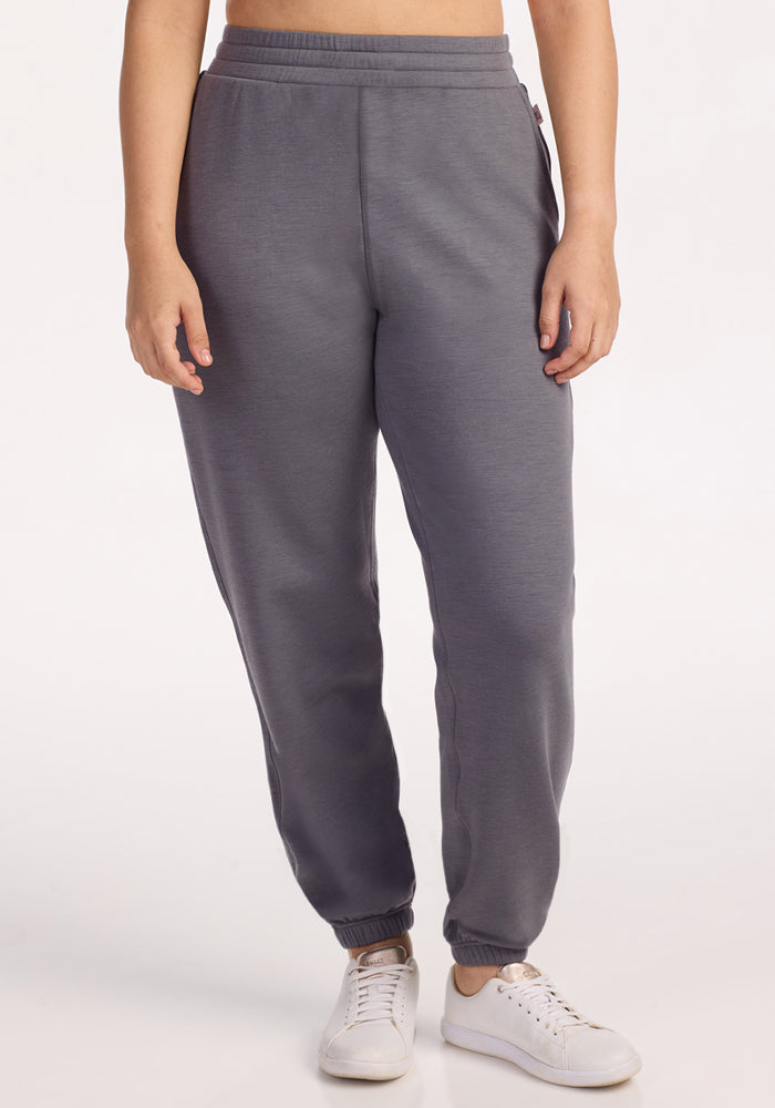 A person models Woolx Parker Sweatpants in Arctic Dusk with white sneakers, standing against a plain light background. The image is cropped from the shoulders down. 