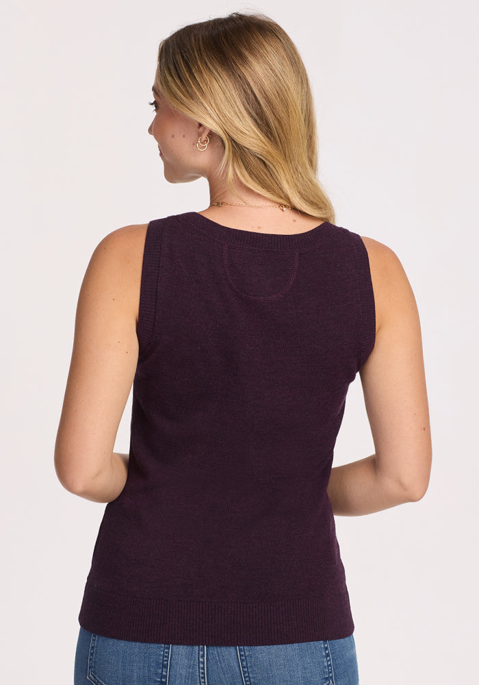 A woman with long, light brown hair is seen from behind wearing the Woolx Chessy Tank Top in Deep Plum and blue jeans, set against a plain light background.