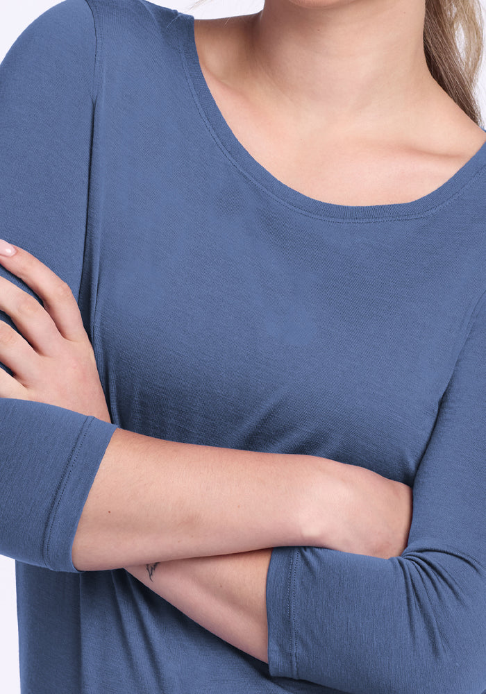 A person wearing a blue Woolx Jenny 3/4 Sleeve Crew Neck - Skyline crosses their arms across their chest, showing only the lower face, neck, and upper torso.