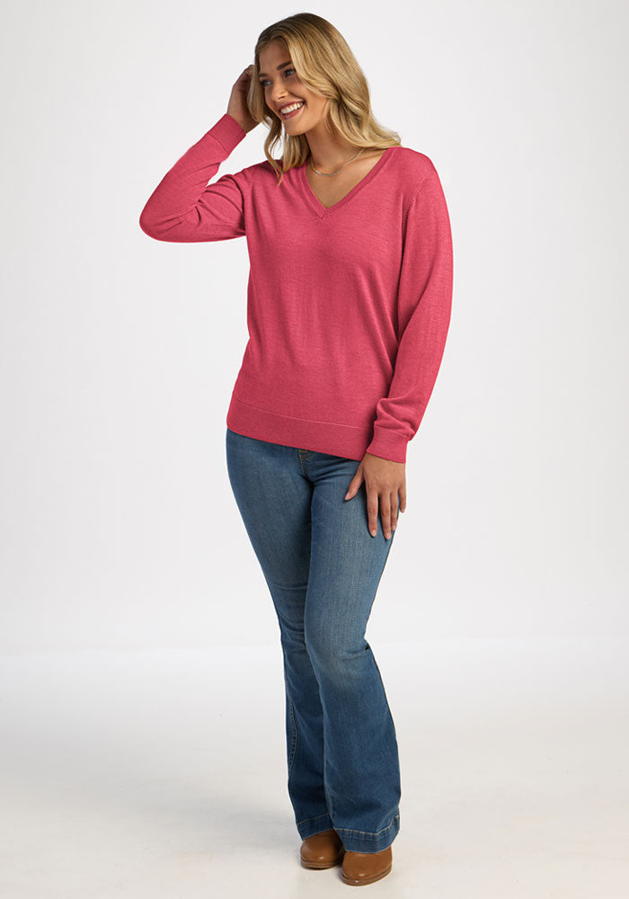 A woman wearing a bright pink V-neck Francesca Sweater - Vivid Rose and blue jeans.