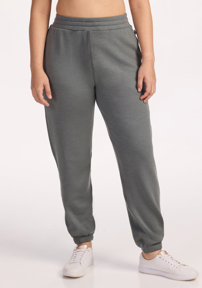 A person wearing Woolx Parker Sweatpants in Sedona Sage stands against a plain white background, white sneakers on their feet and upper body partially out of frame. 