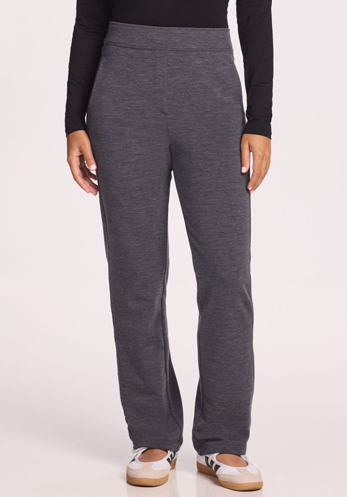 A person wearing Woolx Emerson Straight Leg Pants Petite in Cinder Melange, a long-sleeve black top, and white sneakers stands facing the camera against a plain light background with hands relaxed by their sides.