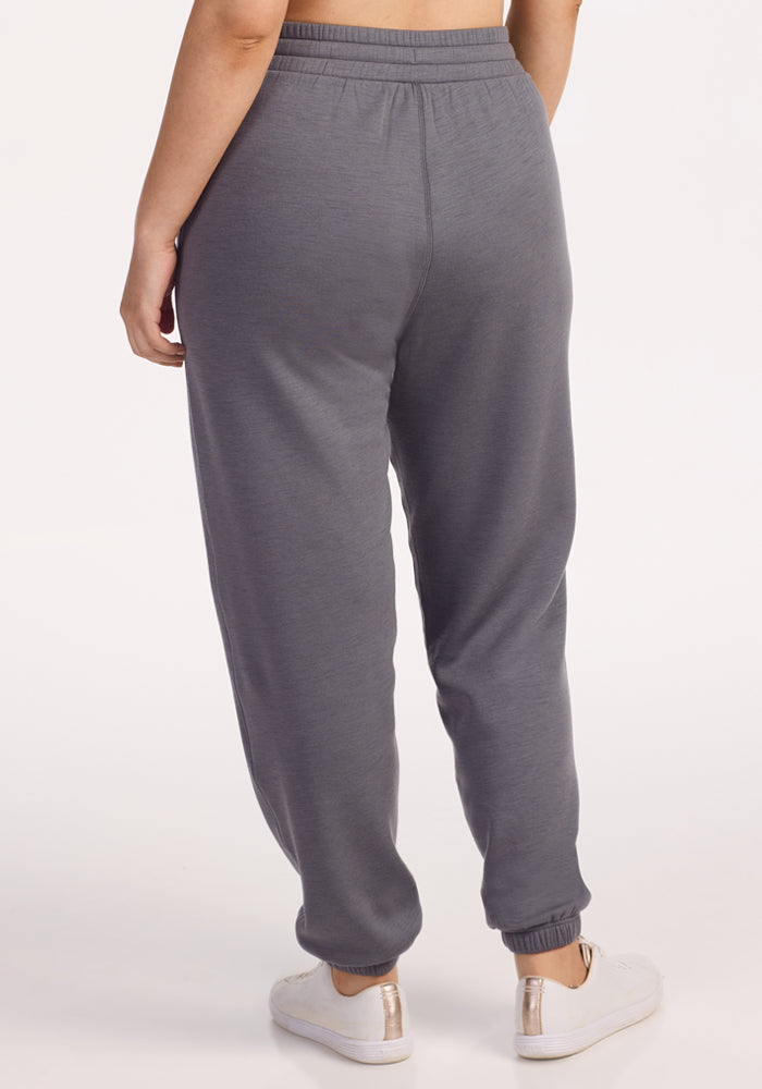 A person shown from the waist down, wearing Woolx Parker Sweatpants in Arctic Dusk and white sneakers, viewed from the back against a plain white background.