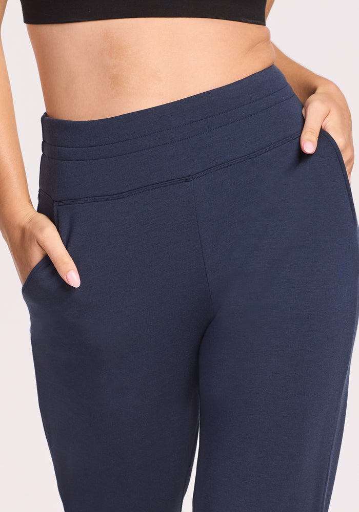 A person in a black crop top and Woolx Willa Joggers - Deep Navy, hands in pockets, shown from mid-torso to thighs against a light background.