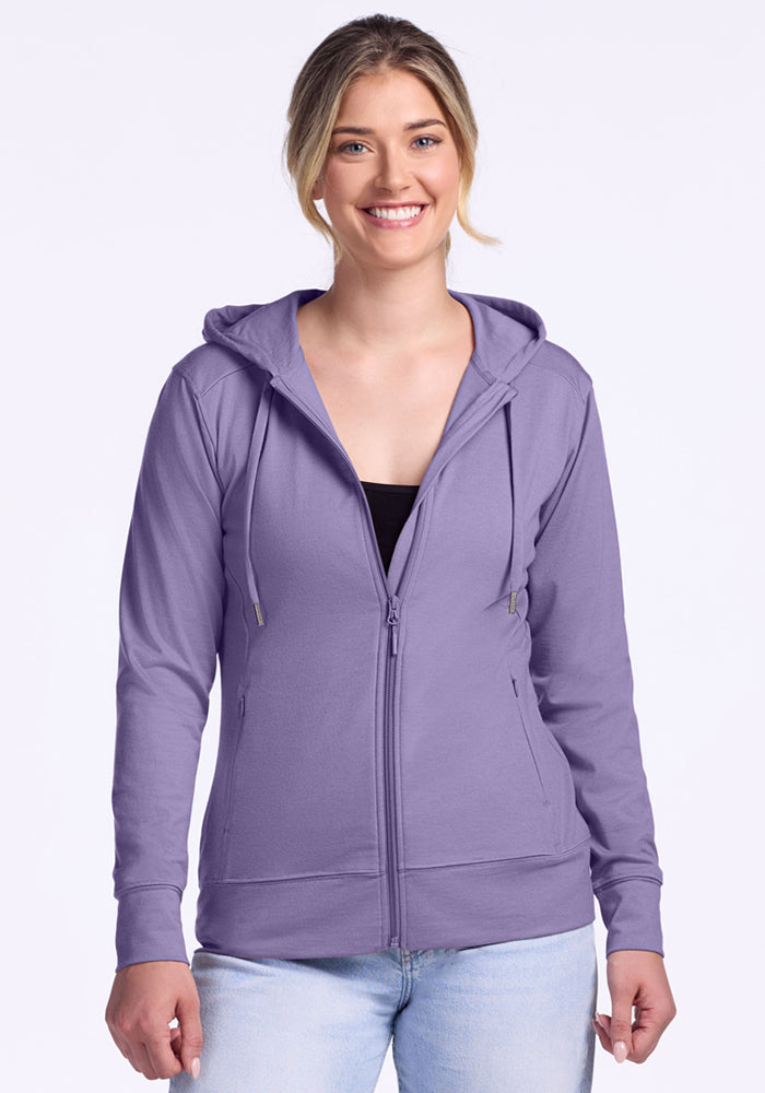 A smiling woman with blonde hair in a ponytail wears the Woolx Ryann Hoodie in Montana Grape over a black top and light blue jeans, standing against a plain white background. 