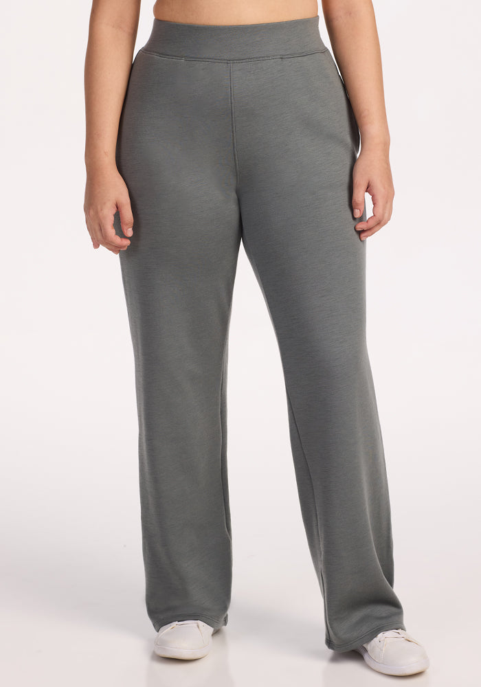 A person models Woolx Bree Lounge Pants in Sedona Sage, featuring a relaxed fit, paired with white sneakers and standing facing forward against a plain white background. The image is cropped just below the shoulders.