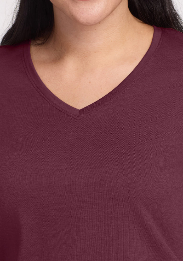 A close-up of a person wearing the Woolx Junie V Neck in Grape Harvest, showing only their lower face, neck, shoulders, and upper chest against a plain background.