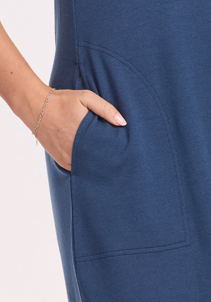 A close-up of a hand with a delicate bracelet rests in the pocket of the Woolx Cassie Dress - Starry Night. The soft, slightly stretchy fabric may offer moisture-wicking comfort, making it perfect for travel.