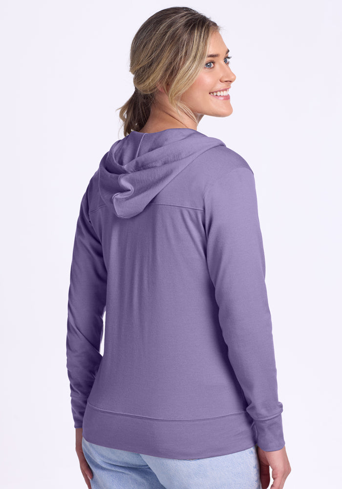 A woman with blonde hair in a ponytail wears the Woolx Ryann Hoodie in Montana Grape and light blue jeans, standing with her back to the camera and smiling over her shoulder against a plain white background.