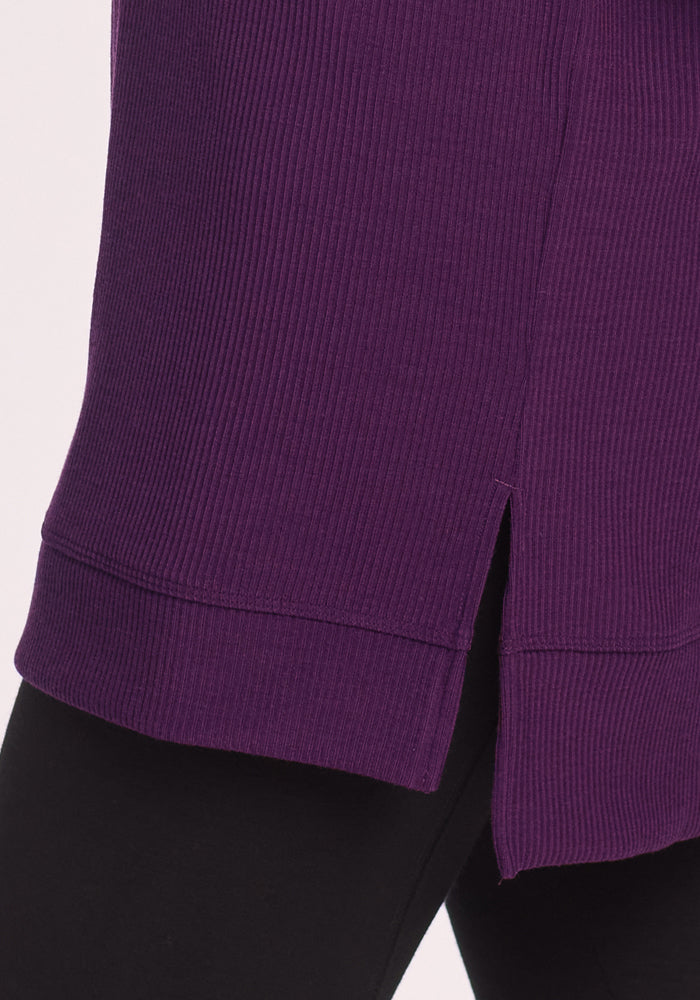 Close-up of the Woolx Evie Ribbed Tunic in Majestic Purple, a cozy Merino wool top with a side slit at the hem, styled over black leggings.