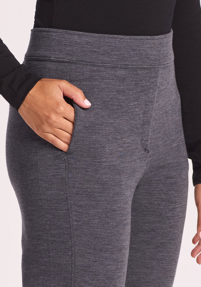 A person wearing Woolx Emerson Straight Leg Pants Petite in Cinder Melange and a black long-sleeve top has their right hand in the pants pocket.