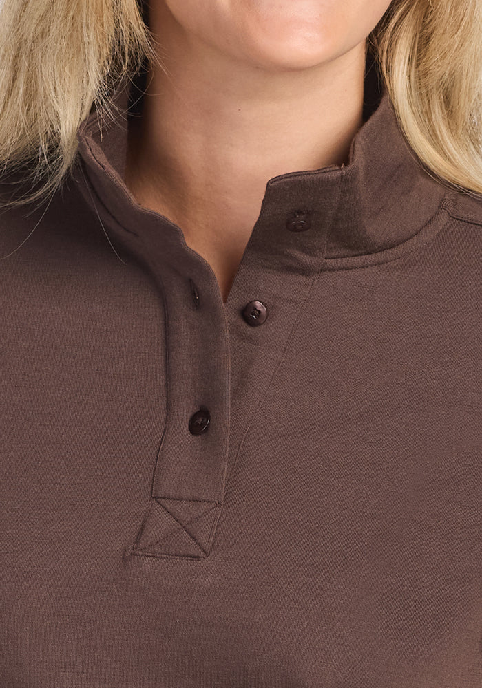 Close-up of a person wearing the Woolx Annie 3 Button Pullover in Bracken, featuring three undone buttons at the top. Focus is on the odor-resistant merino wool sweater’s neckline and collar; light skin and blonde hair are partially visible.