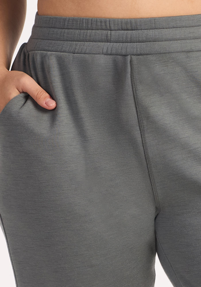 Close-up of a person wearing Woolx Parker Sweatpants in Sedona Sage, with their right hand in the pocket. The image highlights the waistband and upper leg, showcasing their comfort and moisture-wicking Merino wool—perfect for travel.