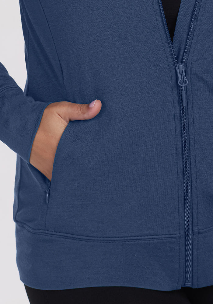 A person wearing the Woolx Ryann Hoodie - Starry Night, lightweight and partially unzipped to reveal a black shirt, right hand in the front pocket. Shown waist to mid-thigh—an essential layer for travel or any adventure.