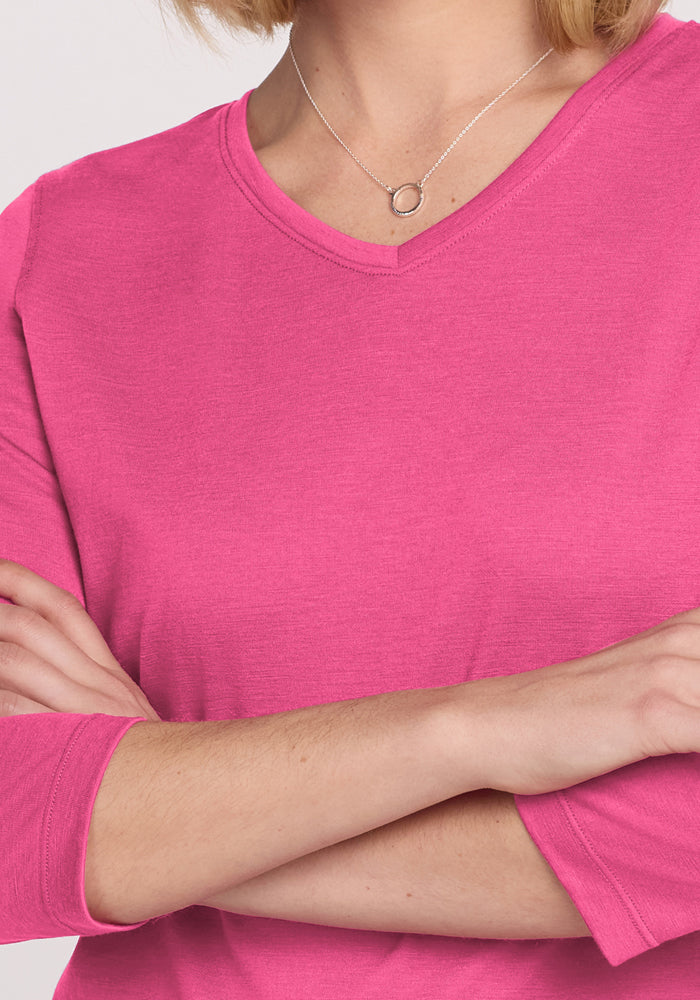A person wearing the Woolx Elena 3/4 Sleeve V Neck in Raspberry Fizz, with arms crossed, visible from shoulders to mid-torso, and a silver necklace with a circular pendant.