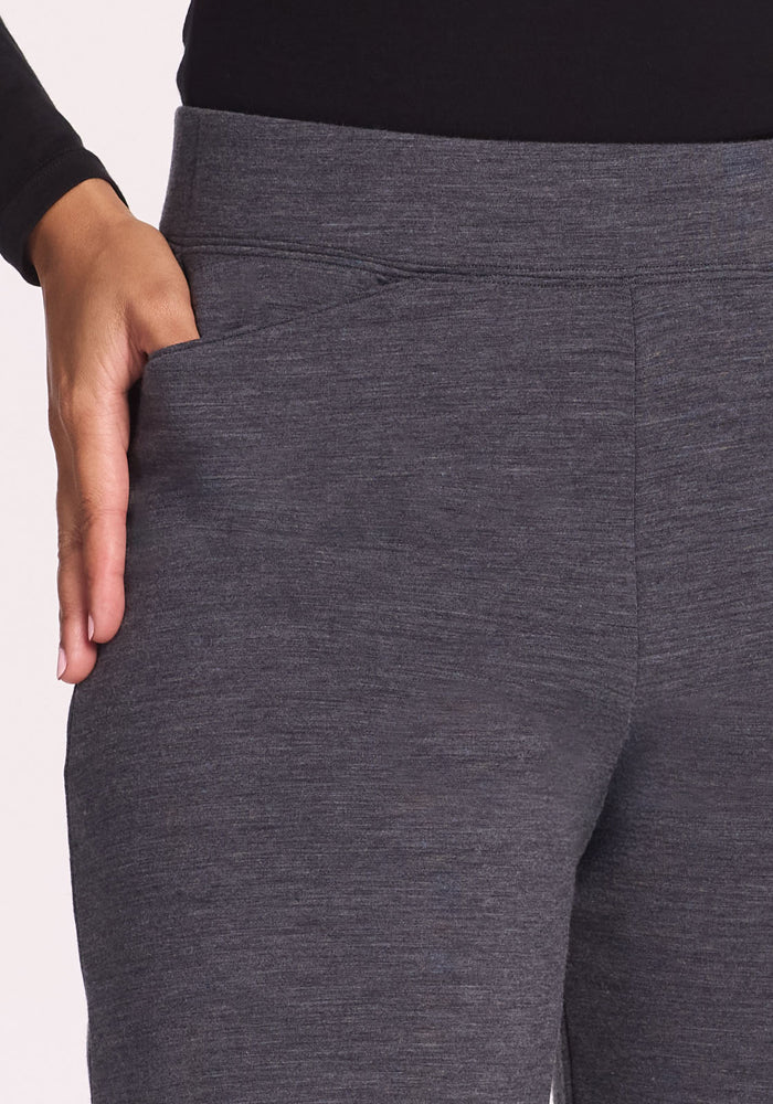 A person wearing Woolx Ellie Wide Leg Pants Petite in Cinder Melange and a black top has their left hand placed in the pants' left pocket.