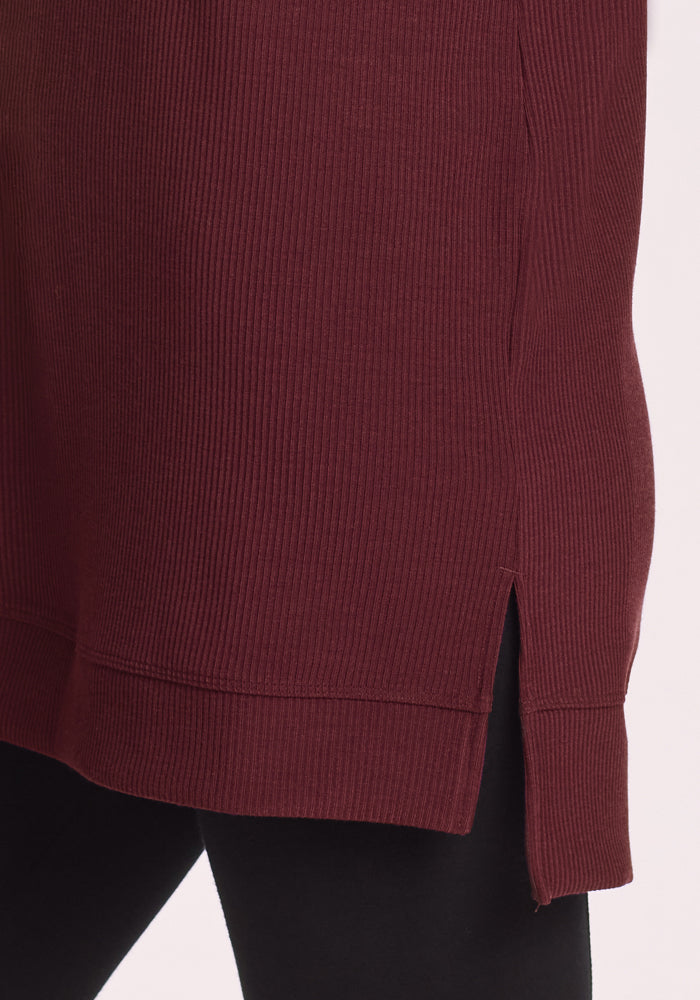 Close-up of the side slit on the Woolx Evie Ribbed Tunic in Toasted Garnet, showing a black layer underneath—crafted from Merino wool for comfortable temperature regulation.