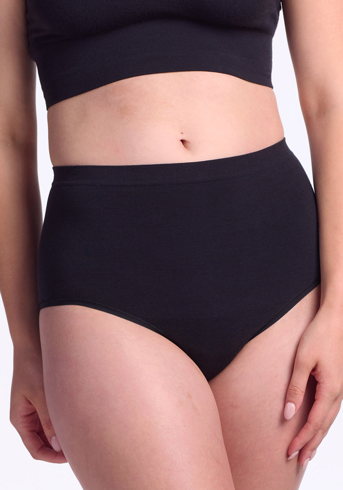 Model shown mid-torso to upper thighs wears Woolx Mabel Full Coverage Underwear in black, set against a plain background, emphasizing seamless comfort.