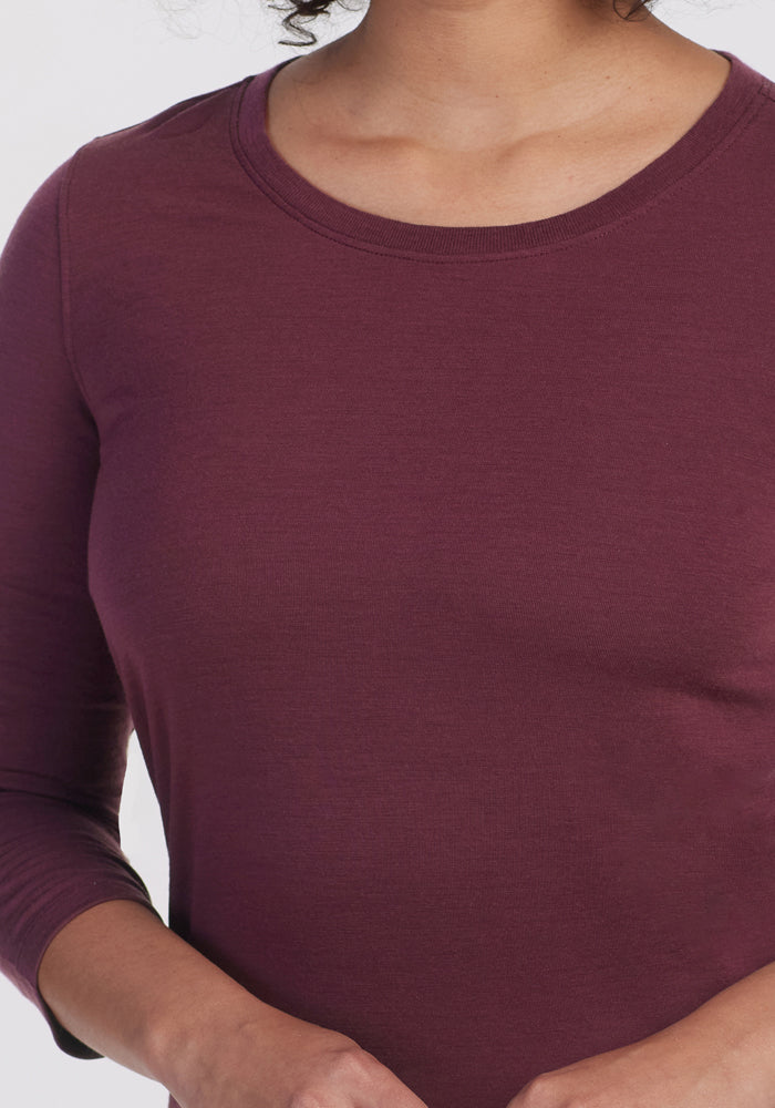 A person wearing the Woolx Jenny 3/4 Sleeve Crew Neck in Grape Harvest. The image is cropped to show the upper torso and part of the face, with hands partially visible at the bottom.