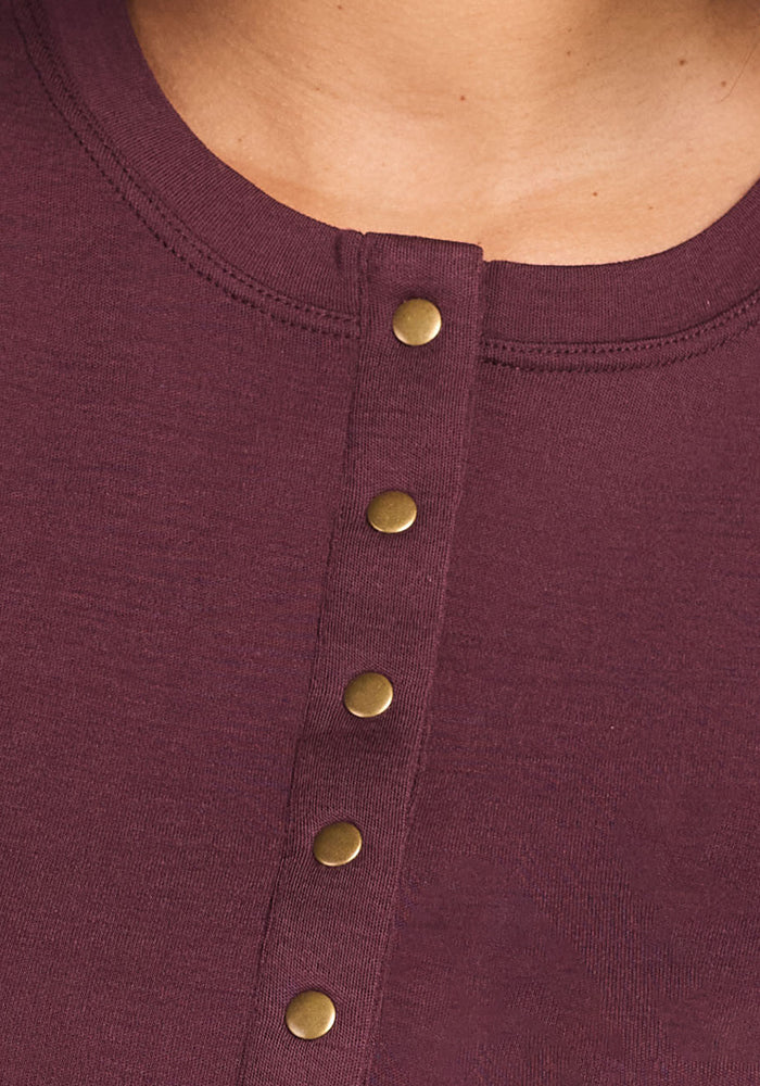 Close-up of the upper chest wearing the Woolx Charlotte Puff Sleeve Top in Chocolate Fig, featuring a round neckline and a front row of gold-colored Henley-style snap buttons.