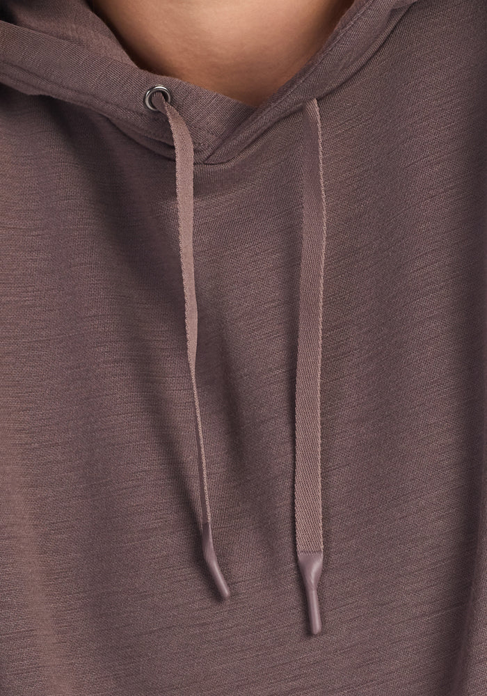 Close-up of a person wearing the Woolx Avery Hoodie in Plum Truffle, showcasing the antimicrobial fabric’s texture, two drawstrings, and the bottom of the hood, with part of the lower face visible at the top.