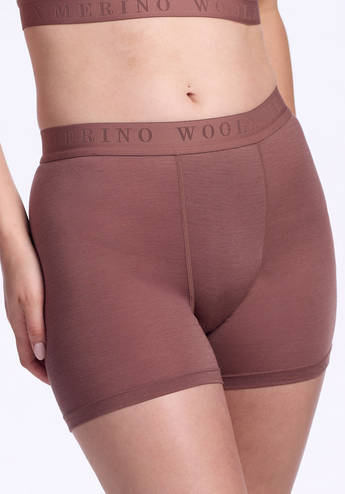 A person wears Woolx Elliott Boyshort in nutmeg, high-waisted antimicrobial merino wool underwear with a matching branded waistband. The photo is cropped from mid-chest to mid-thigh.