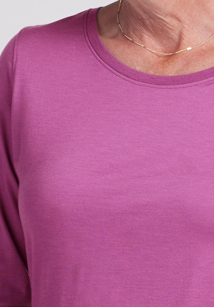 A close-up of a person wearing the Woolx Jenny 3/4 Sleeve Crew Neck in Purple Wine and a thin gold necklace, with only the lower part of their face and neck visible.