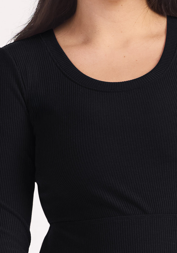 Close-up of a person in the Woolx Caroline Ribbed Twirl Dress—black, long sleeves, round neck, wrinkle-resistant.