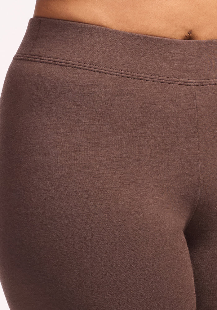 Close-up of a person wearing Woolx Stella Tall - Bracken leggings, highlighting the high-waisted fit, textured DuraLite fabric, and waistband details against a light background.