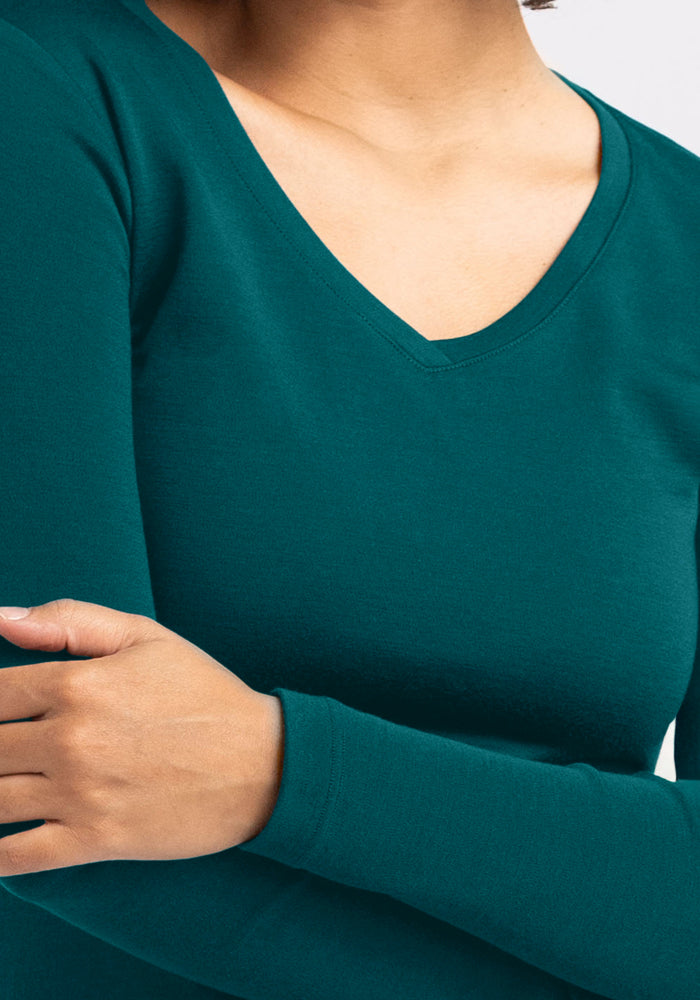 A person wears the Woolx Eva Tunic in Riverbank Green with arms loosely crossed; only the torso and part of the arms are visible.