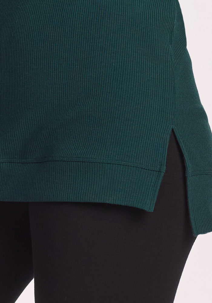 Close-up of the Woolx Evie Ribbed Tunic in Deep Timber, a cozy women's Merino wool top featuring a ribbed texture and side slit, paired with black pants. The photo highlights the lower hem and temperature-regulating fabric.