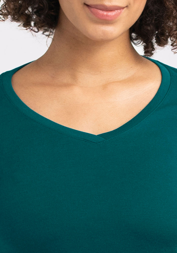 A woman with curly hair models the Woolx Eva Tunic in Riverbank Green, shown from shoulders up to just above her lips.